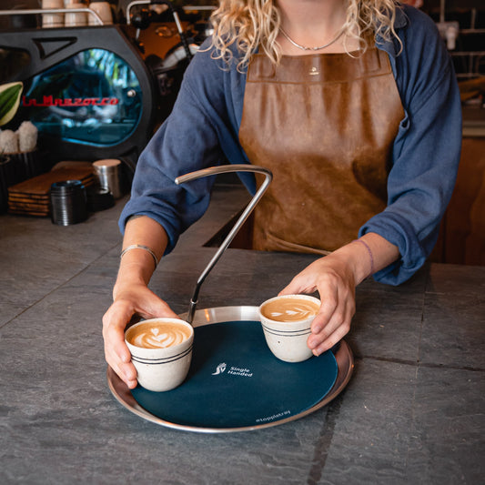 Barista serving two lattes on the Topple Tray with the navy mat